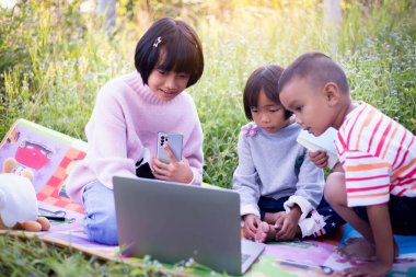 Çocuklar büyüteçle ormanda keşfe çıkıyorlar.