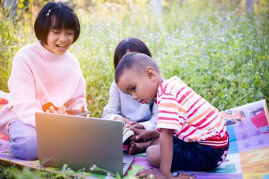 Çocuklar büyüteçle ormanda keşfe çıkıyorlar.