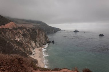 ABD 'nin Kaliforniya eyaletinde kayalıkları ve uçurumları olan Big Sur kıyı bölgesi, bulutlu bir günde, ABD' nin Bixby Köprüsü yakınlarında çekilen fotoğraf