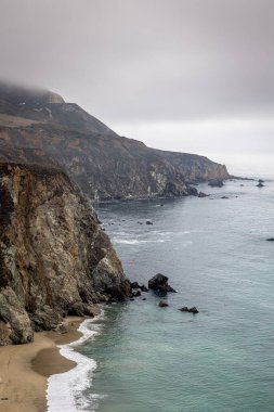 ABD 'nin Kaliforniya eyaletinde kayalıkları ve uçurumları olan Big Sur kıyı bölgesi, bulutlu bir günde, ABD' nin Bixby Köprüsü yakınlarında çekilen fotoğraf