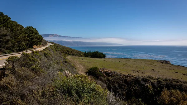 加利福尼亚美丽的西海岸 沿着1号公路 有草地和岩石 蓝天和大海 还有远处的残雾 — 图库照片