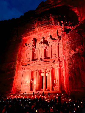 Geceleri yerde oturan insanların büyük grup, rock Al Khazneh veya Hazine, Petra, Ürdün mimarisini kesti..