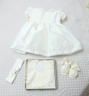 Beyaz bir elbise, ayakkabı, önlük ve saç bandıyla vaftiz töreni için bir bebek hazırlıyorum.