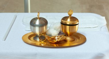 Altın tepside vaftiz töreni için bir gümüş, bir altın kadeh, bir altın kabuk ve bir beyaz mum da dahil olmak üzere dini eşyalar var.