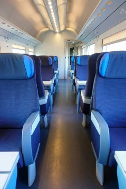 İstasyonda yolcuların binmesi için mavi koltuklu boş modern tren bekliyor.