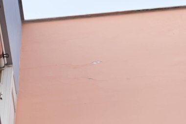 Çatlak ve yaşlanma belirtileriyle dolu pembe duvar, yenileme ve bakım ihtiyacını vurguluyor