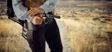 Sert bir kovboy klasik bir batı tarzı düellodan sonra silahını ayarlar. Geleneksel kostüm içinde bir sonraki atış için hazır bekliyor.