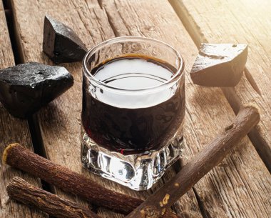 Bir bardak meyan kökü özütü, saf bloklar ve kırsal ahşap bir masaya yapışan çubuklar, alternatif tıp konsepti.