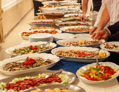 Şefler uzun bir açık büfe masasında çeşitli lezzetli yemekler hazırlıyorlar. Restoranda ya da otel ortamında servis edilmeye hazır.