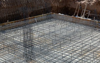 Çelik takviye çubukları inşaat sahasındaki bir yapı için şebeke yapısı oluşturuyor, beton dökülmesine hazırlanıyor