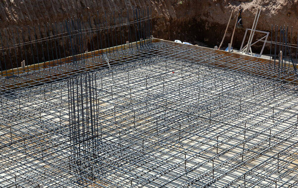 Steel reinforcement bars forming a grid structure for a building foundation at a construction site, preparing for concrete pouring