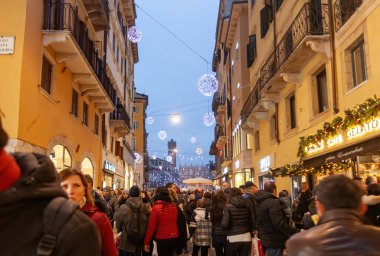 Verona, İtalya - 08 Aralık 2017: İnsanlar Verona, İtalya 'da bir alışveriş caddesinde yürüyor, Noel süsleriyle süslenmiş, neşeli bir atmosfer yaratıyorlar.