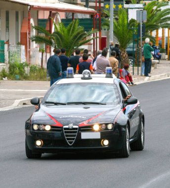 Mondragone, Italy - May 30, 2009: Italian carabinieri police car, an alfa romeo 159 sportwagon, patrolling a street with flashing blue lights, ensuring public safety and order clipart