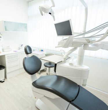 Parlak ve modern dişçi ofisi profesyonel ekipmanlar, rahat bir sandalye ve bir monitör ile temiz ve davetkar bir atmosfer yaratıyor.
