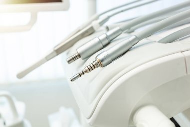 Modern bir dişçi koltuğunda dinlenen diş matkaplarını kapatın ve çağdaş diş bakımının gelişmiş teknolojisini ve steril ortamını vurgulayın.