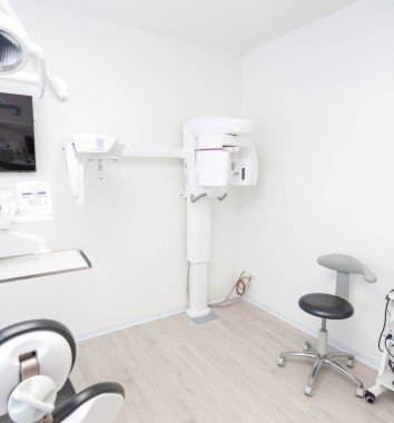 Interior of a bright, modern dental clinic showcasing an orthopantomograph, other specialized equipment, and a clean, professional environment clipart