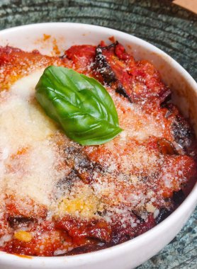 Patlıcan, patlıcan, patlıcan, domates sosu, mozzarella ve parmesan içeren taze fesleğen yaprağı katmanları.