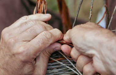 Sanatçının ellerini kapayın hasır dallar örerek geleneksel tekniklerle el yapımı bir sepet yapın.