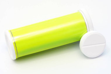 Sağlığı, tıbbı ve ilaç kavramlarını temsil eden, beyaz bir zemin üzerinde duran coşkun bir tableti ve sarı tüpü kapatın.