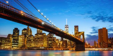 Brooklyn Köprüsü alacakaranlıkta Manhattan 'ı New York şehrinin üzerinde yükselen bir Dünya Ticaret Merkezi' ne bağlayan canlı ve ikonik bir şehir manzarası.