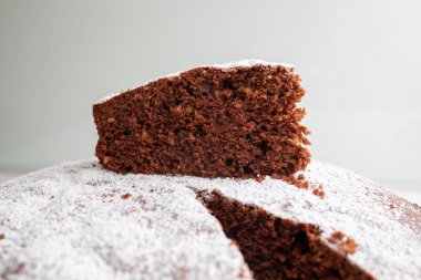 Üzerinde pudra şekeri serpiştirilmiş Caprese keki, pastanın geri kalanının üzerine konur ve görsel olarak çekici bir sunum oluşturur.