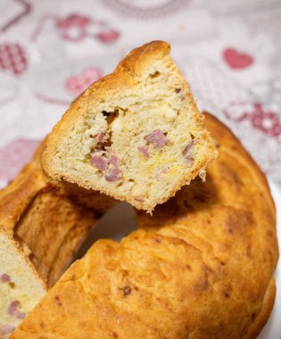 Salam, peynir ve biberle dolu geleneksel lezzetli bir pasta olan bir dilim Napolitan tortano 'nun yumuşak dokusunu ve zengin bileşenlerini gözler önüne seriyor.