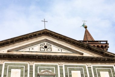 Collegiata di Sant 'Andrea' nın Empoli, Toskana 'daki ön cephesi, kırmızı tuğlalı çan kulesinin yanında rüzgar gülü ile yeşil ve beyaz mermer geometrik desenler sergiliyor.