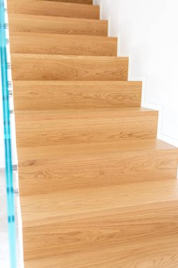 Işık çağdaş bir eve akar, parlak cam bir balyoz ile yüzen bir meşe merdivenini aydınlatarak modern bir zarafet ve sofistike tasarım atmosferi yaratır.