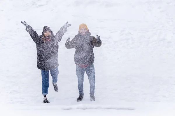 Couple throwing snow and enjoying winter time in field, full of snow. Couple throwing snow and enjoying winter.