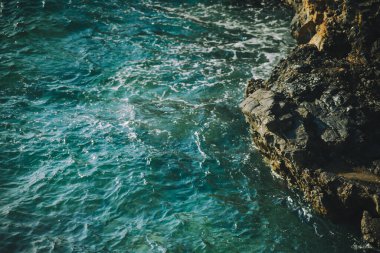 Ege Denizi 'nin mavi-mavi okyanus dalgaları engebeli kayalara çarpar ve canlı su ile doğal kıyı şeridi arasında çarpıcı bir kontrast yaratır.