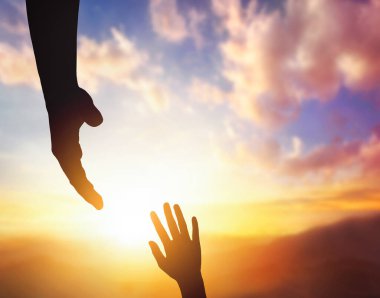 Silhouettes of helping hand,  hope and support each other on sunset background.