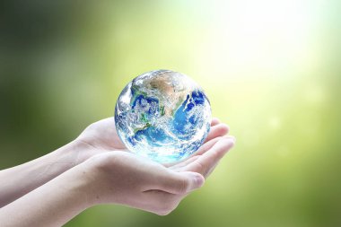 Bulanık yeşil arka plan üzerinde dünyayı tutan insan elleri. Bu görüntünün elementleri NASA tarafından desteklenmektedir