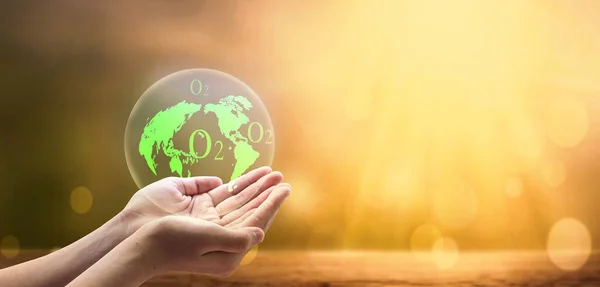 Earth day concept, A green earth globe in human hands over blurred global warming background