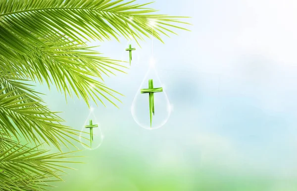 Palm Sunday concept, Cross made of palm leaves hanging on palm leaves on blue sky background