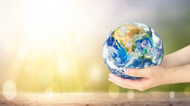 Dünya Günü, doğanın bulanık arka planında dünyayı tutan insan elleri. Bu görüntünün elementleri NASA tarafından desteklenmektedir