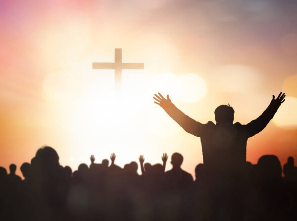 Easter and Good Friday concept,Silhouette human raising hand to praying God on blurred cross  sunset background