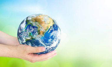  Dünya Çevre ve Toprak Günü, Dünya 'yı bulanık yeşil ve mavi gökyüzü arka planının üzerinde tutan insan elleri. Bu görüntünün elementleri NASA tarafından desteklenmektedir