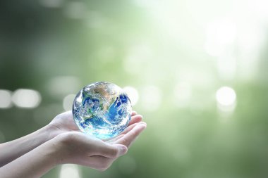Dünya Çevre Günü konsepti: Bulanık yeşil arka planda Dünya 'yı tutan insan elleri. Bu görüntünün elementleri NASA tarafından desteklenmektedir
