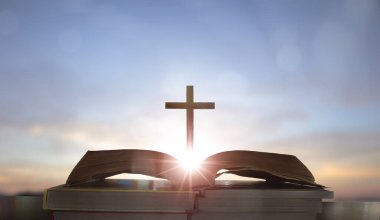 Gündoğumu arkaplanlı açık İncil üzerinde çapraz