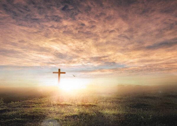 Christian wooden cross on sunset background.