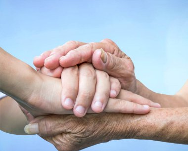 Mavi arka planda el ele tutuşan yaşlı ve genç, 