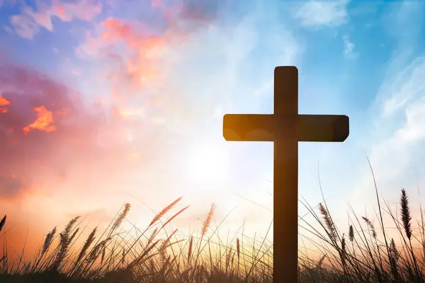 stock image The cross on grass with sunset in the sky background