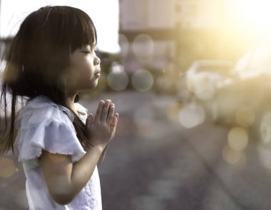 Küçük Asyalı kızın eli Gün doğumunda dua ediyor.