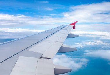 Açık mavi gökyüzü, tüylü süslemeli kümülüs bulutları, bir uçaktan panoramik manzara, kanat yakın çekim..