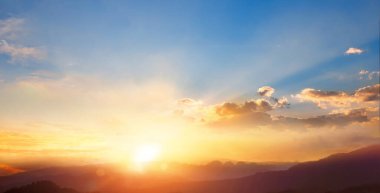 Gün doğumunda, alçak bulutlu bir gökyüzünün altındaki dağlar üzerinde manzara.