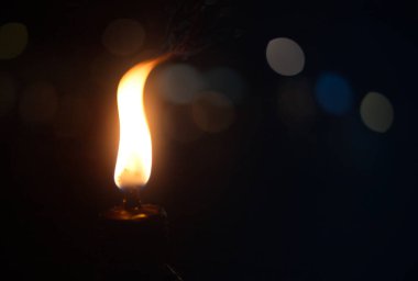 Bokeh efektli koyu bir arkaplanda mum yakılıyor.