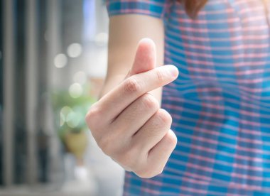Woman hand showing thumbs up gesture with blur background,vintage tone