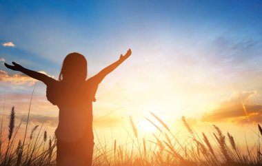 Silhouette of happy young woman open arms with sunset sky background