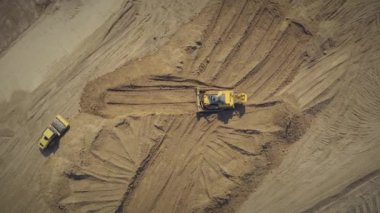 Yol yapım ekipmanları inşaat alanında çalışıyor: bir yol silindiri ve buldozer yolun inşaatı için kum tabanını hazırlıyor. Üst görüntü insansız hava aracı görüntüsü.