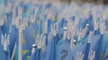 A symbol of the struggle of Ukrainians for freedom and democracy. The War for the Independence of Ukraine. Many flags of Ukraine with coats of arms tridents on a pole close-up.